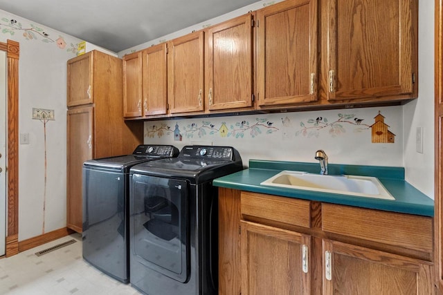 washroom with a sink, cabinet space, washer and clothes dryer, visible vents, and light floors