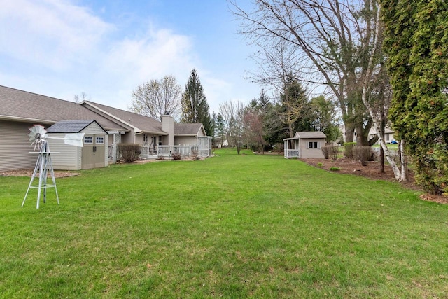 view of yard featuring a storage unit, an outdoor structure, and a deck