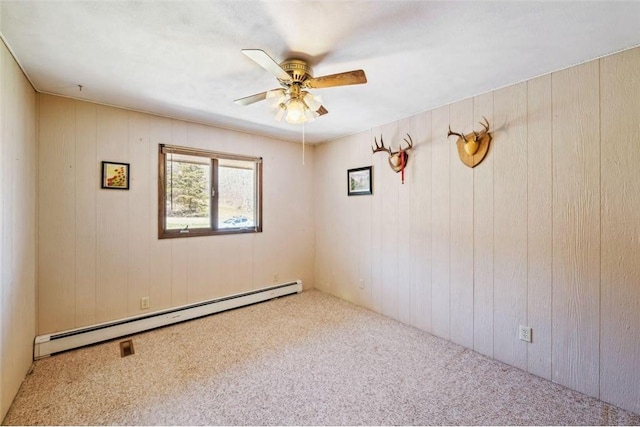 carpeted spare room featuring a baseboard radiator, wood walls, and ceiling fan