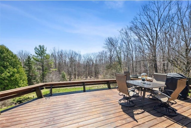 deck featuring a view of trees and outdoor dining space
