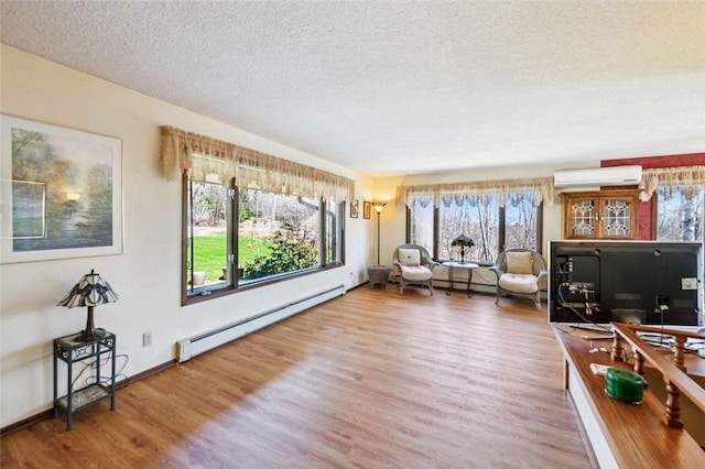 living area with a textured ceiling, an AC wall unit, wood finished floors, and a baseboard heating unit