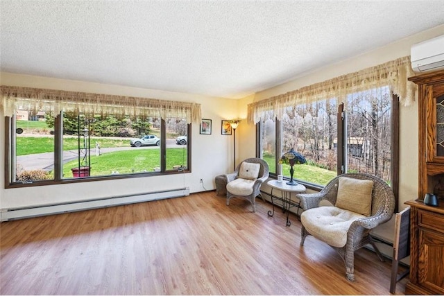 living area featuring a textured ceiling, plenty of natural light, wood finished floors, and a baseboard heating unit