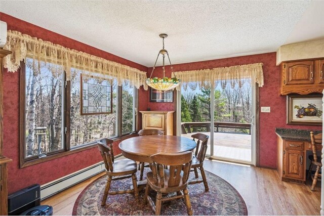 dining area with a textured ceiling, an AC wall unit, light wood-style flooring, and baseboard heating