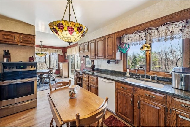kitchen featuring stainless steel range with electric stovetop, light wood-style flooring, a sink, pendant lighting, and dishwasher