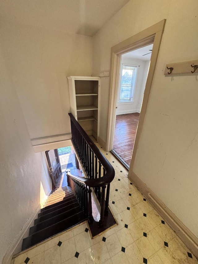 stairway with baseboards and tile patterned floors