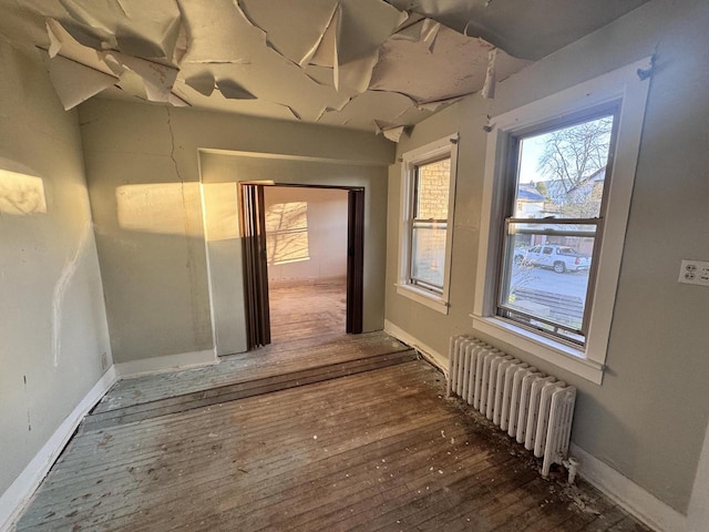 interior space with baseboards, radiator, and hardwood / wood-style flooring
