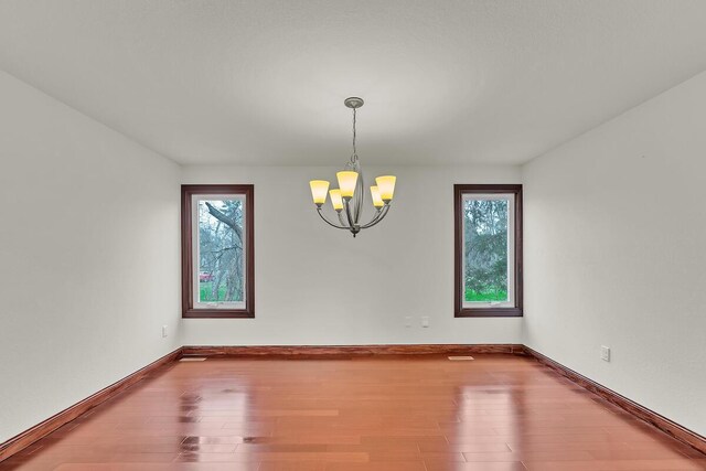 8408 N Lake Dr, Fox Point, WI 53217 - unfurnished room with a wealth of natural light, wood finished floors, baseboards, and a notable chandelier