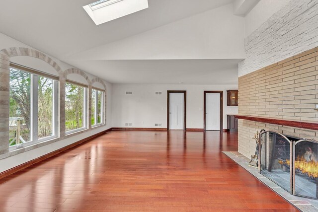 8408 N Lake Dr, Fox Point, WI 53217 - unfurnished living room featuring wood finished floors, a skylight, a brick fireplace, and high vaulted ceiling