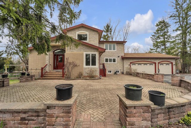 8408 N Lake Dr, Fox Point, WI 53217 - mediterranean / spanish house with entry steps, brick siding, a garage, and fence