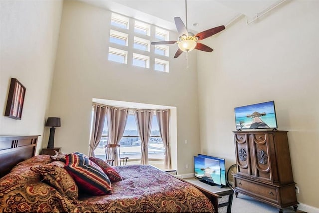 bedroom with carpet, multiple windows, baseboards, and a high ceiling