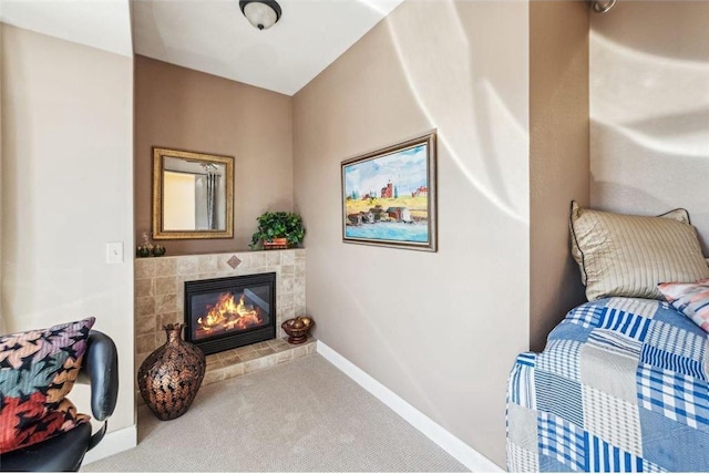 living area featuring a tile fireplace, carpet, and baseboards