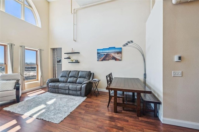 living room featuring baseboards, a towering ceiling, and wood finished floors