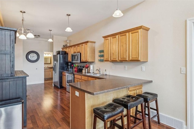 kitchen featuring dark wood-style floors, stainless steel appliances, dark countertops, and visible vents