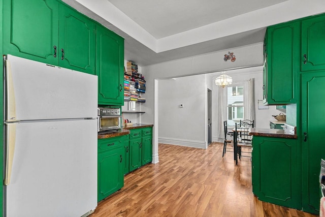 kitchen with freestanding refrigerator, dark countertops, a toaster, and light wood-style floors