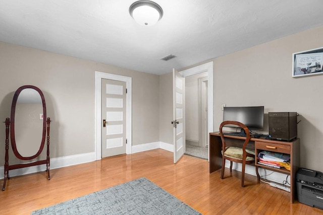 office area with light wood-style flooring, baseboards, and visible vents