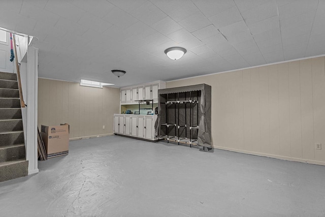 finished basement with baseboards, stairway, and wood walls