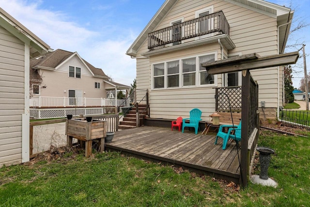 rear view of property featuring fence, a deck, a lawn, stairway, and a balcony