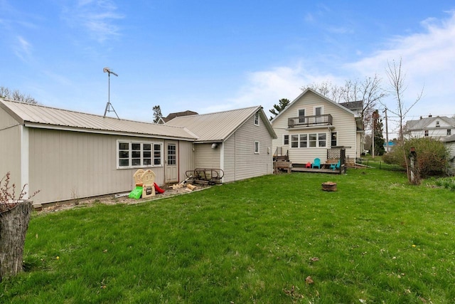 back of house with metal roof, a lawn, and a balcony