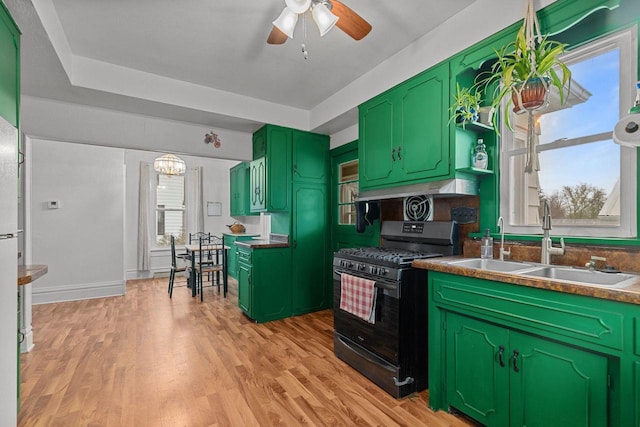 kitchen featuring a sink, ceiling fan with notable chandelier, black range with gas stovetop, green cabinets, and light wood-style floors