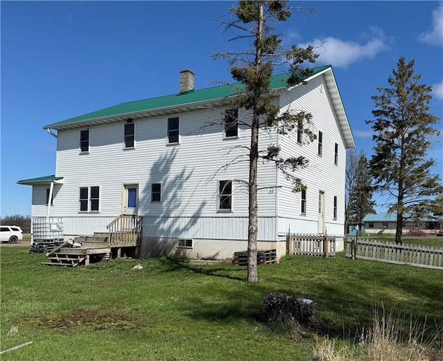 rear view of property with a chimney, fence, and a lawn