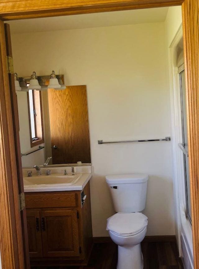 W8918 County Rd W, Crivitz, WI 54114 - half bathroom featuring toilet, baseboards, vanity, and wood finished floors