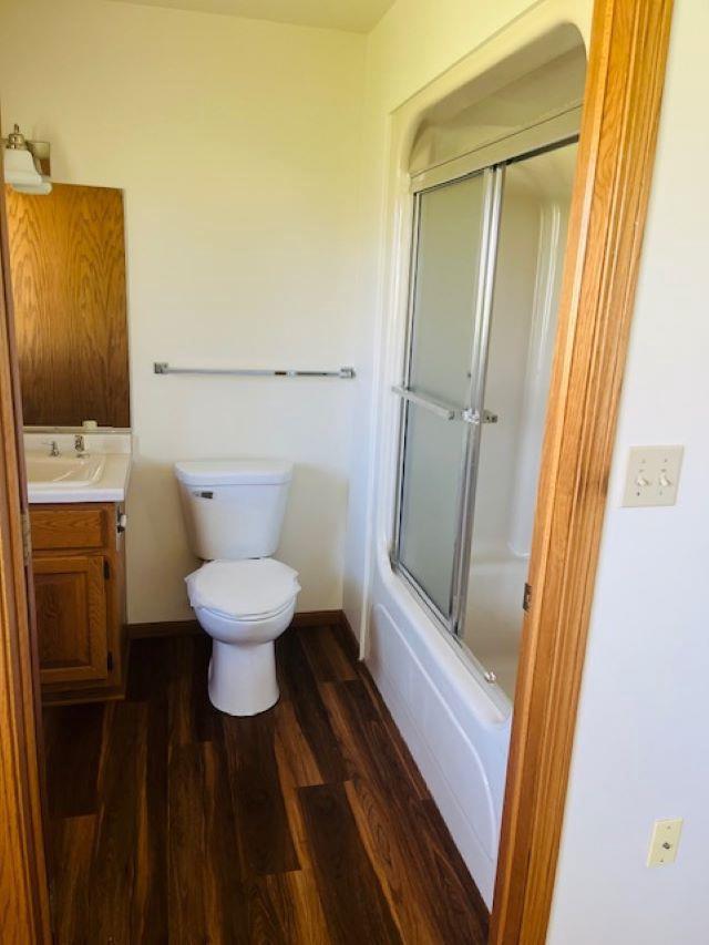 W8918 County Rd W, Crivitz, WI 54114 - full bath with wood finished floors, vanity, toilet, baseboards, and enclosed tub / shower combo
