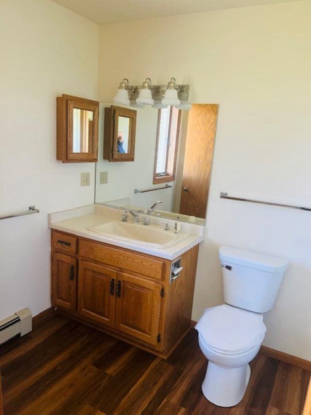 W8918 County Rd W, Crivitz, WI 54114 - half bathroom featuring wood finished floors, vanity, toilet, and a baseboard radiator