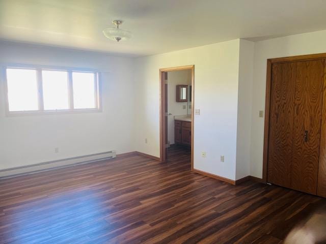 W8918 County Rd W, Crivitz, WI 54114 - unfurnished bedroom featuring dark wood-style floors, a baseboard radiator, baseboards, a closet, and connected bathroom