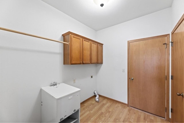washroom with baseboards, hookup for an electric dryer, light wood-type flooring, and cabinet space