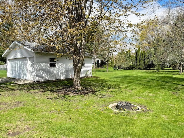 view of yard featuring an outdoor fire pit, a garage, and an outbuilding