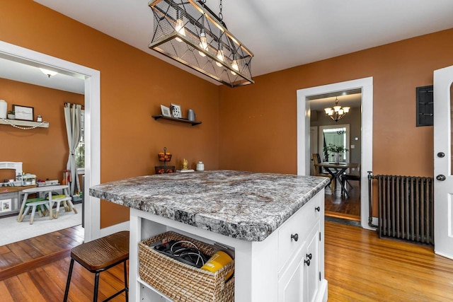 320 W Harrison St, Shullsburg, WI 53586 - kitchen with radiator, decorative light fixtures, a chandelier, white cabinetry, and light wood-style floors