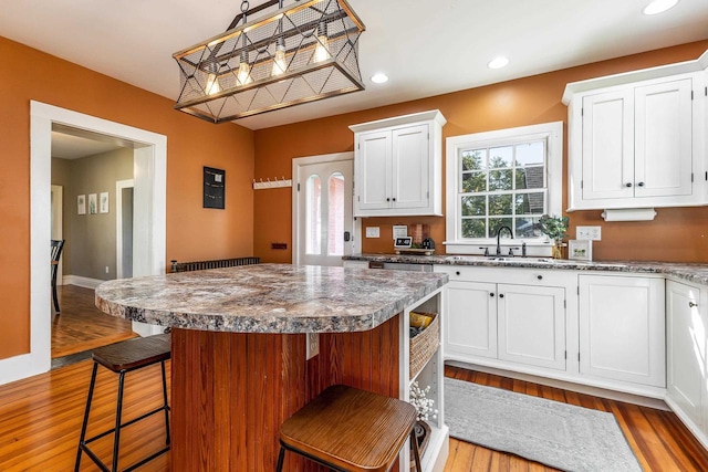 320 W Harrison St, Shullsburg, WI 53586 - kitchen featuring white cabinetry, wood finished floors, a breakfast bar area, and a sink