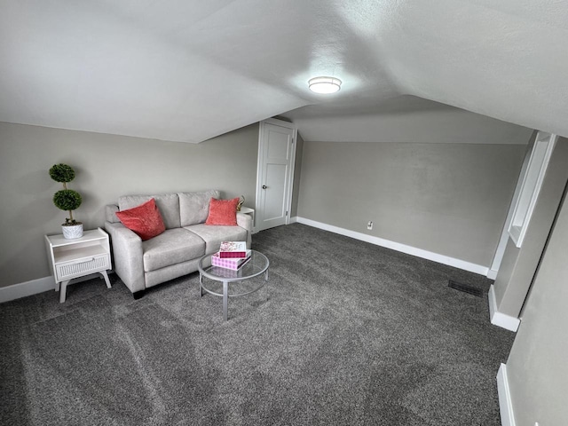 living room with vaulted ceiling, baseboards, visible vents, and dark carpet