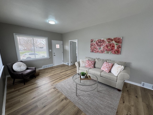 living room with baseboards, visible vents, and wood finished floors
