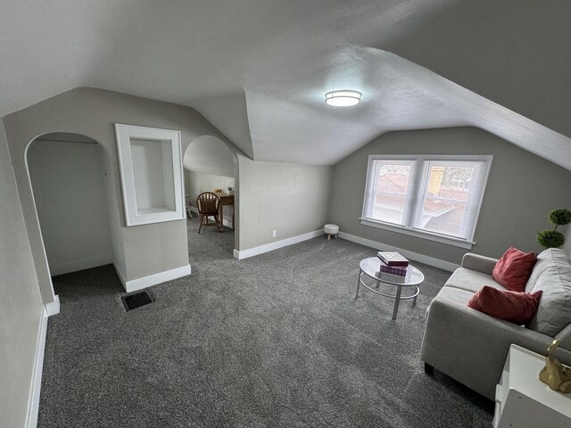 additional living space featuring lofted ceiling, baseboards, dark colored carpet, and visible vents