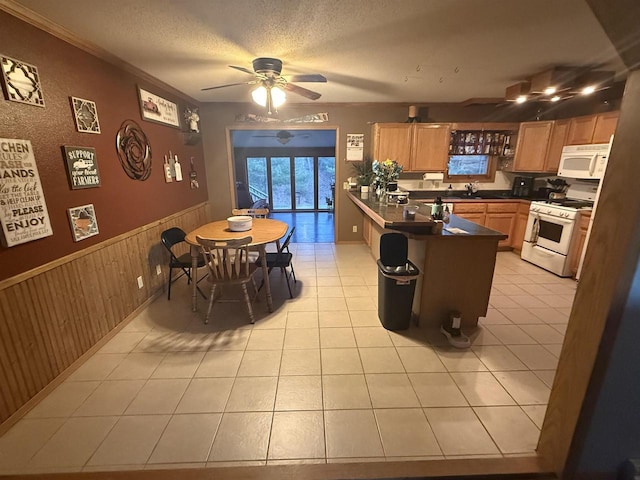 W5417 Volling Ln, Mauston, WI 53948 - kitchen featuring white appliances, a peninsula, dark countertops, a wainscoted wall, and ceiling fan