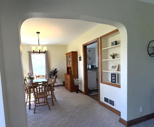 140 W Manchester St, Markesan, WI 53946 - dining area featuring baseboards, an inviting chandelier, visible vents, arched walkways, and light carpet