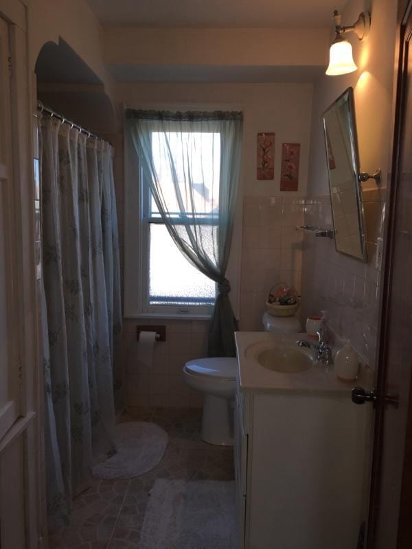 2753 N 60th St Unit 2755, Milwaukee, WI 53210 - bathroom with tile walls, toilet, a shower with shower curtain, tile patterned floors, and vanity