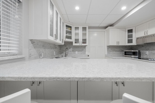 1430 Park Ave, West Bend, WI 53090 - kitchen with a sink, stainless steel microwave, under cabinet range hood, backsplash, and white cabinets
