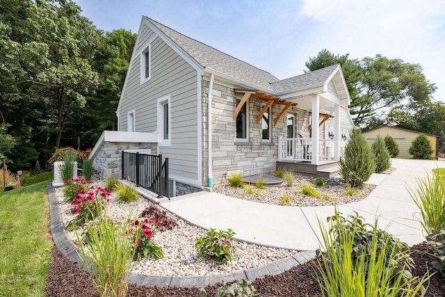 1430 Park Ave, West Bend, WI 53090 - view of front of home with stone siding, a porch, and roof with shingles