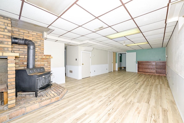 7113 E County Rd E, South Range, WI 54874 - unfurnished living room with a wood stove, wood finished floors, a wainscoted wall, and a paneled ceiling