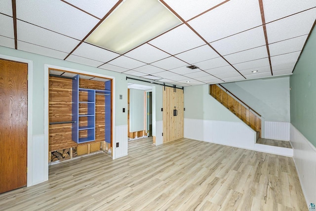 7113 E County Rd E, South Range, WI 54874 - unfurnished living room with wood finished floors, a drop ceiling, a wainscoted wall, and stairs