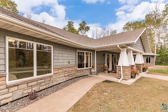 4527 E Marquardt Rd, Superior, WI 54880 - doorway to property with stone siding, a shingled roof, covered porch, and a yard