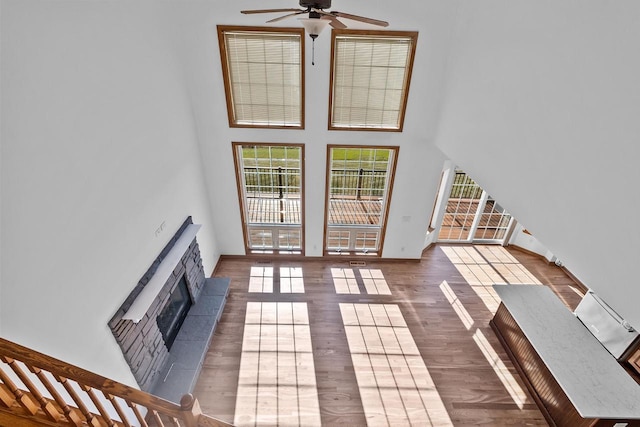 580 S Stone Ridge Dr, Lake Geneva, WI 53147 - unfurnished living room featuring a brick fireplace, a towering ceiling, ceiling fan, and wood finished floors
