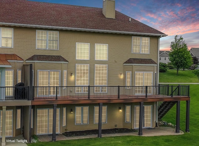 580 S Stone Ridge Dr, Lake Geneva, WI 53147 - back of property at dusk featuring a chimney, a wooden deck, a yard, stairs, and a patio area
