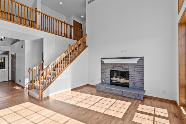 580 S Stone Ridge Dr, Lake Geneva, WI 53147 - unfurnished living room with wood finished floors, a high ceiling, baseboards, stairs, and a fireplace