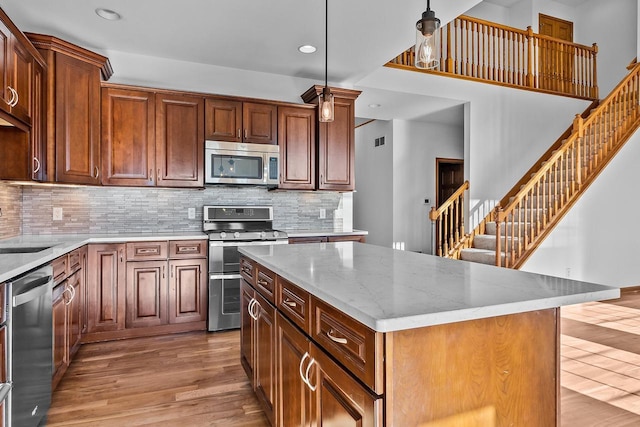 580 S Stone Ridge Dr, Lake Geneva, WI 53147 - kitchen with stainless steel appliances, light wood-style floors, light stone counters, a center island, and recessed lighting