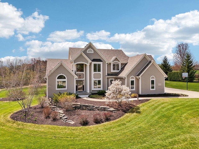 traditional-style house featuring a front lawn and roof with shingles