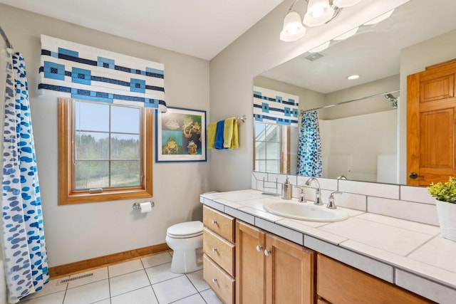 bathroom with healthy amount of natural light, baseboards, tile patterned flooring, and toilet