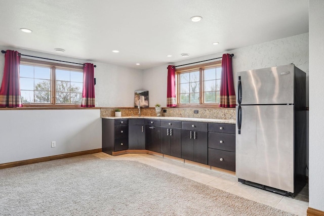 kitchen with freestanding refrigerator, light countertops, light tile patterned floors, recessed lighting, and dark cabinets